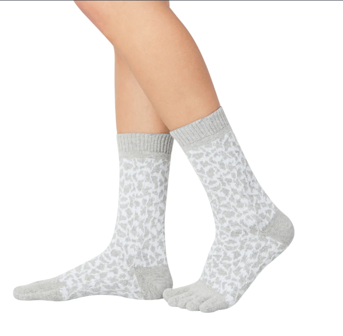 A pair of leopard print midcalf five toe socks worn on a person's feet, with the socks partially pulled down to show the toe separator design.