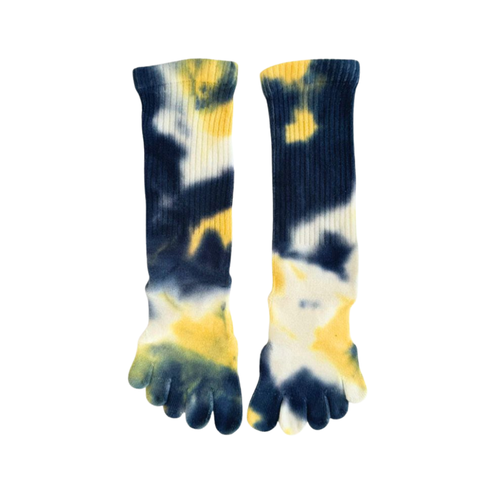A person sitting with Tie die socks in yellow, blue, and gray colors, showing the five separate toe sections and the cushioned sole.