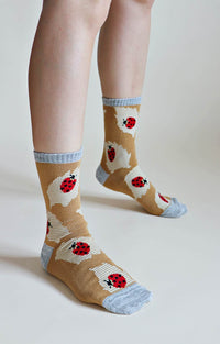 TABBISOCKS brand Replant Pairs Ladybug Organic Cotton Crew Socks in Mustard color with a red ladybug pattern with grayish-gray inserts at the mouth, toe and heel.