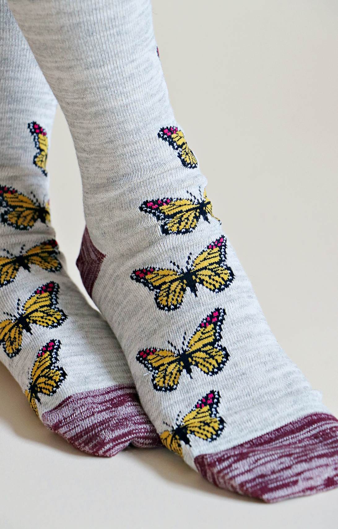 TABBISOCKS brand Replant Pairs "Monarch Butterfly" Organic Cotton Crew Socks with a yellow butterfly pattern with grayish-purple inserts at the mouth, toe and heel in an overall Light Grey color. The socks have a yellow butterfly pattern with grayish-purple inserts at the mouth, toe, and heel.