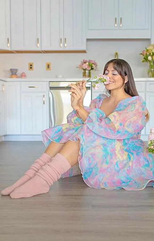 This is a picture of a woman sitting and relaxing with a flower wearing Tabbisocks product name Scrunchy Over The Knee Lounge Wool Blend Socks