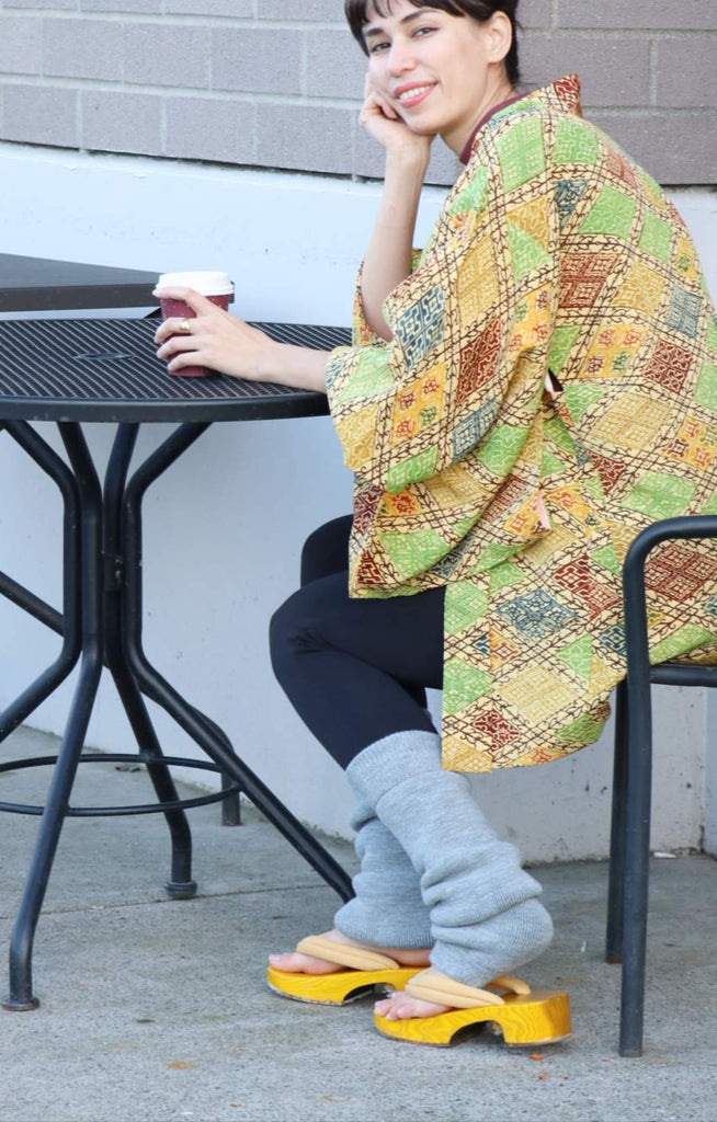 Woman in a colorful kimono sitting at an outdoor table with a coffee cup.