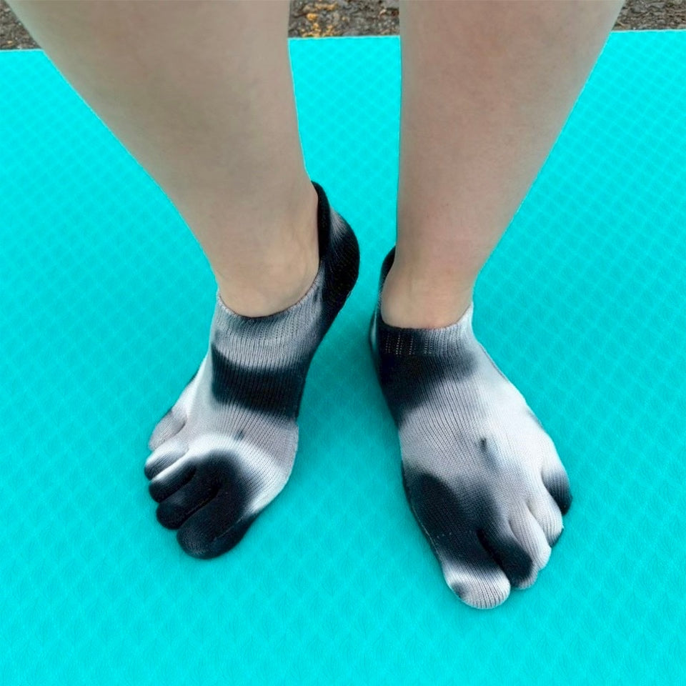 Person wearing black and gray toe socks on a blue mat.