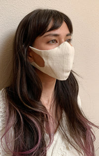 Side view of a woman with long hair wearing the Natural Ivory color of The Japanese Seamless Comfort Face Mask from Tabbisocks Wellness