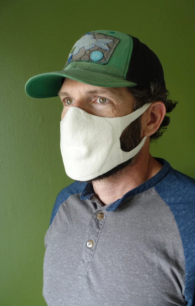 Side view of a man wearing a green cap wearing the Natural Ivory color of The Japanese Seamless Comfort Face Mask by Tabbisocks Wellness
