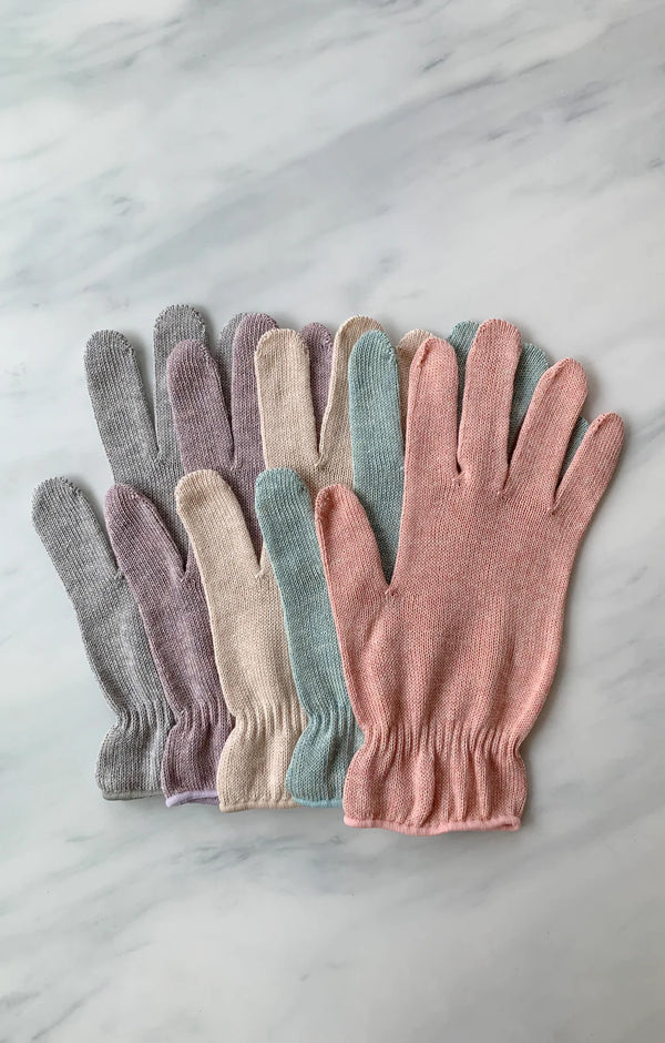 Five colors of Tabi Socks Wellness botanically dyed organic cotton gloves in natural, pink, purple, aqua, and light gray