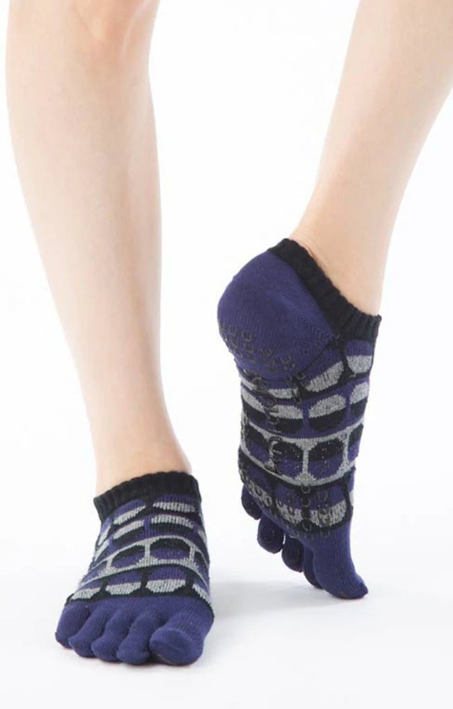 Frontal view of a woman wearing a pair of Knitido plus brand Moon Phase Toe Grip Socks in navy