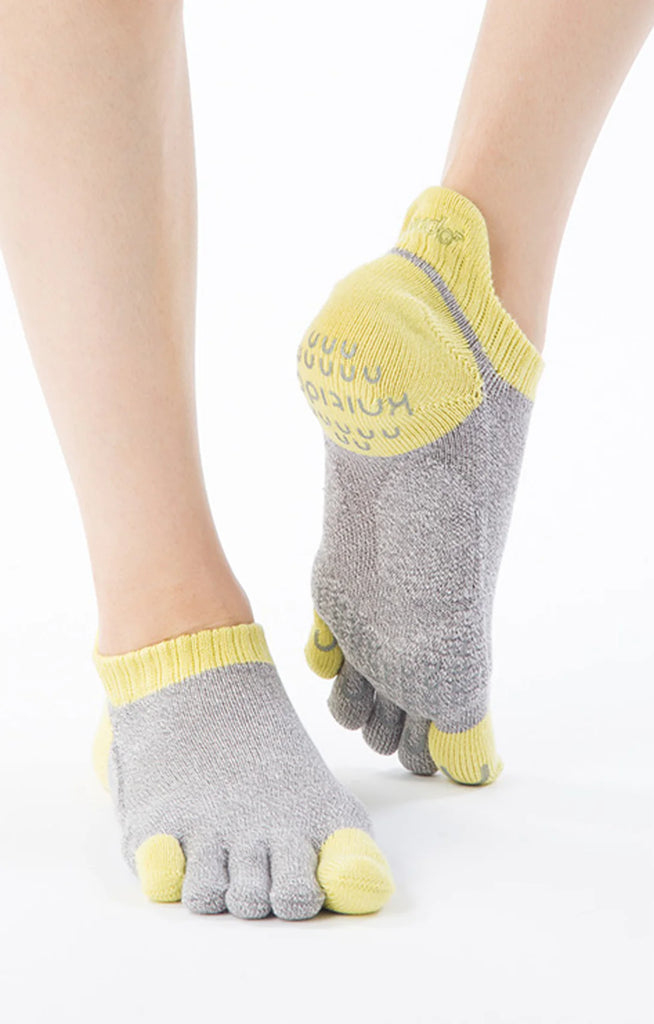 A woman's foot wearing the Yellow color of Two Colors Footie Grip Socks With Power Pads by Knitido plus