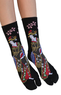 This is a photo of a woman's leg wearing the black color of the product name KABUKI TABI TOE SOCKS of the brand name NINJA SOCKS