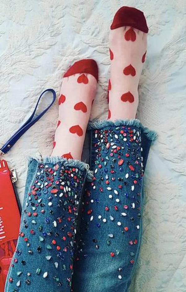 Woman's leg in jeans wearing the RED color of the product Clear Heart Sheer Crew Socks by Tabbisocks