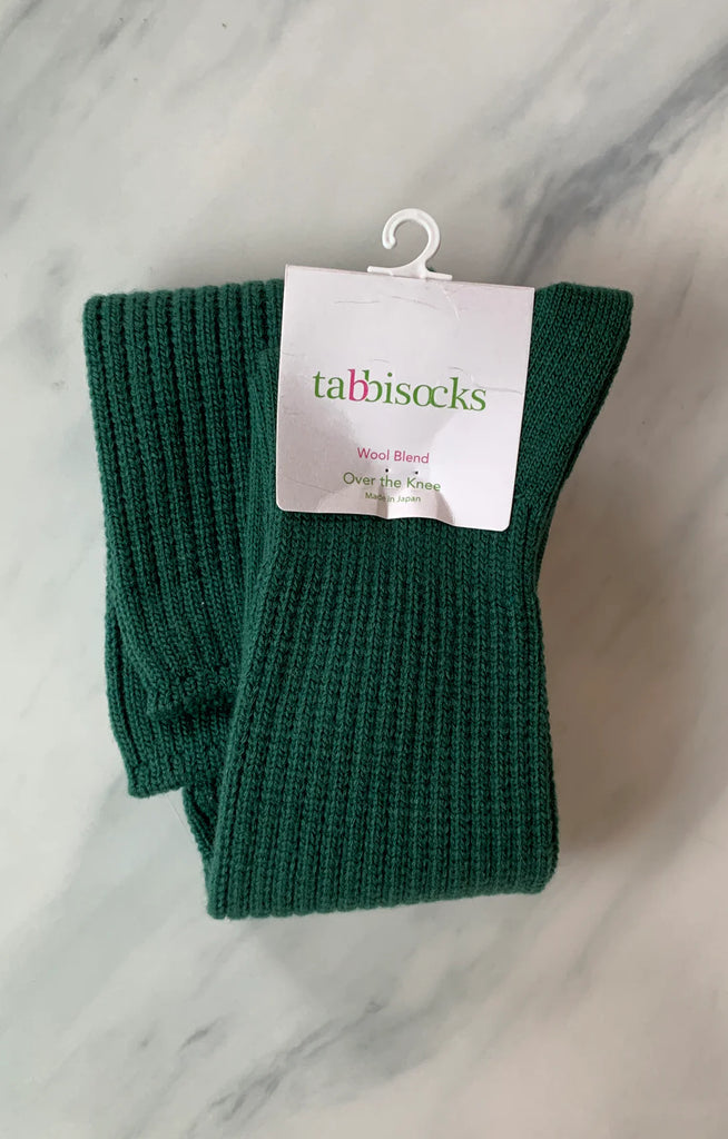 This is a photo of a woman's leg wearing Tabbisocks product name Scrunchy Over The Knee Lounge Wool Blend Socks Spruce Green.