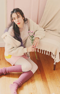This is a picture of a woman with a flower sitting on the floor looking out wearing Tabbisocks product name Scrunchy Over The Knee Lounge Wool Blend Socks