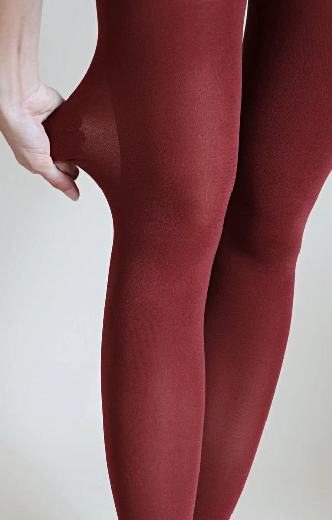 A woman is checking the elasticity of a pair of Tabbisocks 23 Colors Opaque Zokki Tights in the color Nutmeg by pinching and pulling at the knees