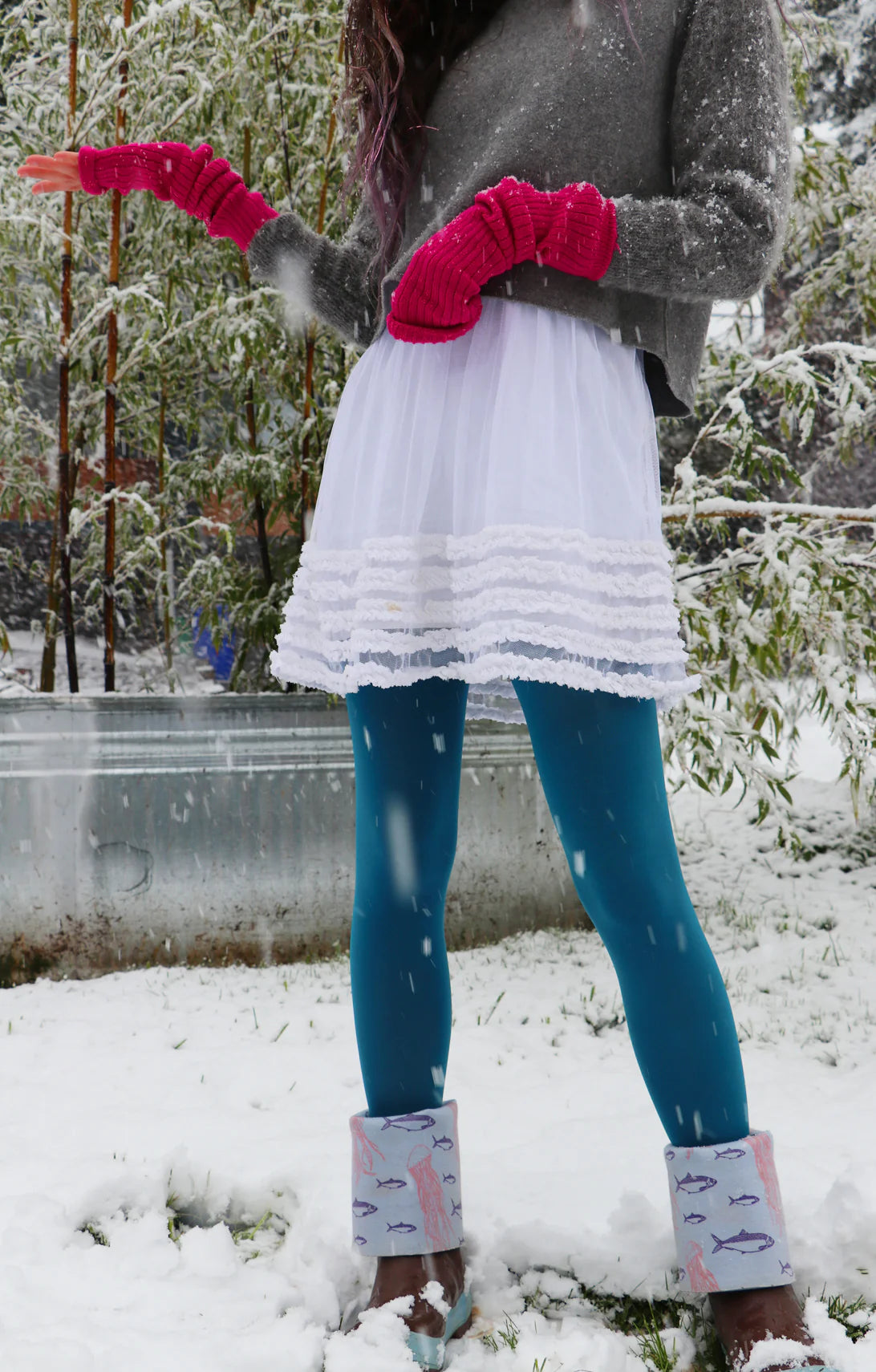 Woman standing in the snow wearing Tabbisocks 23 Colors Opaque Zokki Tights in Teal with a white lace skirt and gray sweater