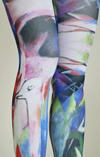 This is a close-up view of the knee area of Tabbisocks' Birds By Franz Marc Printed Art Tights in navy blue. The fabric has a geometric pattern with a bird design on it, and the front side looks bluish.