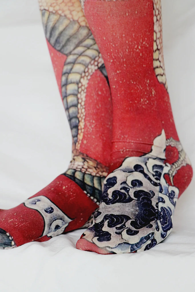 Close-up of a woman's leg in an ivory-colored skirt wearing Tabbisocks Tights-Tabbisocks-Dragon-By-Katsushika-Hokusai-Printed-Art-Tights